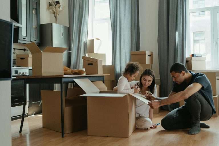 a family sits around cardboard packing boxes preparing to move their household items