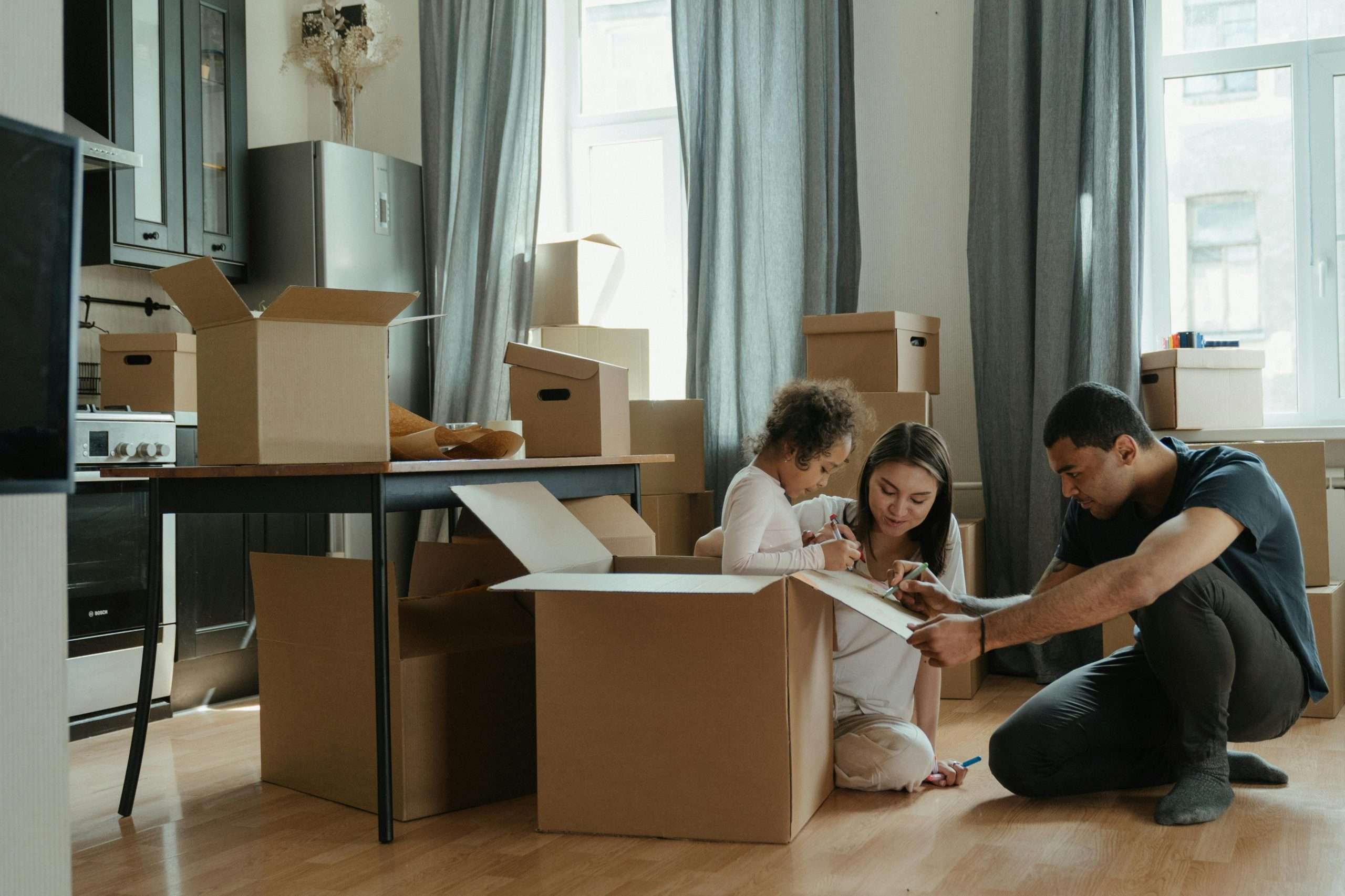 a family sits around cardboard packing boxes preparing to move their household items