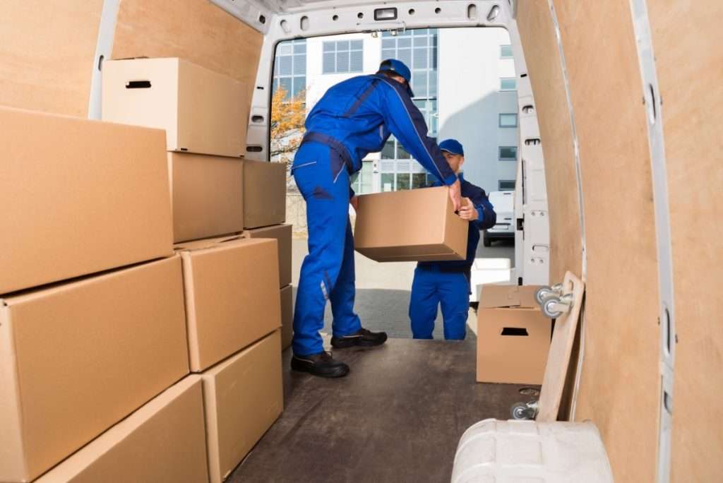 Two Anthem movers in blue jump suits loading boxes into the back of a van