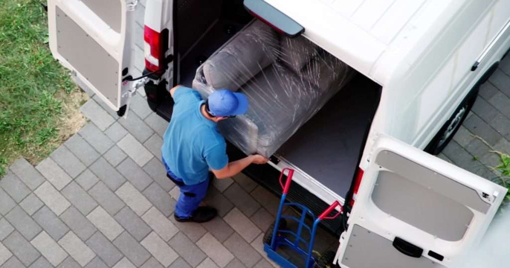 A skilled mover carefully loading items into a white moving van.