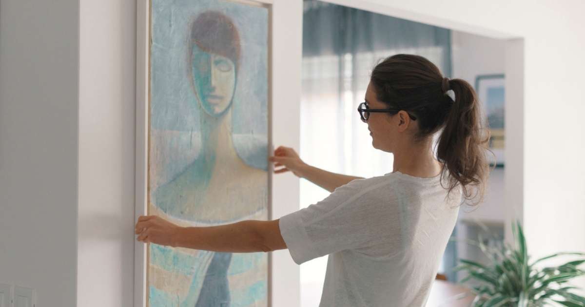 A Phoenix woman hanging up a painting in her home