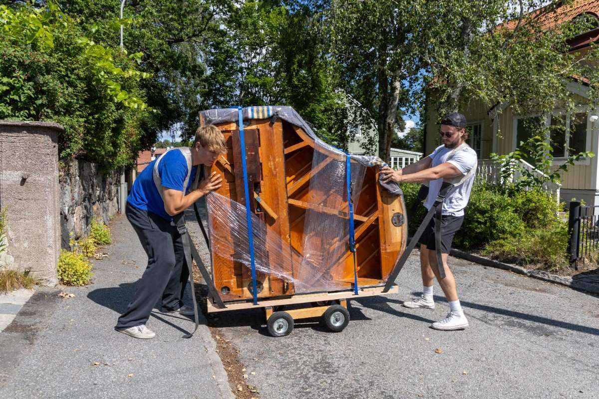 Phoenix piano movers transporting a piano through an alley using a dolly