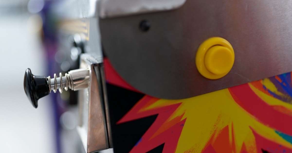 A closeup view of a pinball machine's button and plunger after being moved by a Phoenix specialty moving team