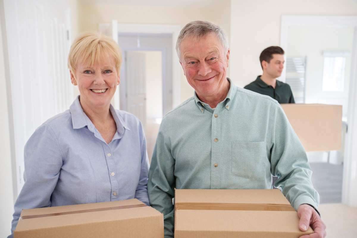 Two Phoenix senior moving customers holding boxes and smiling while moving