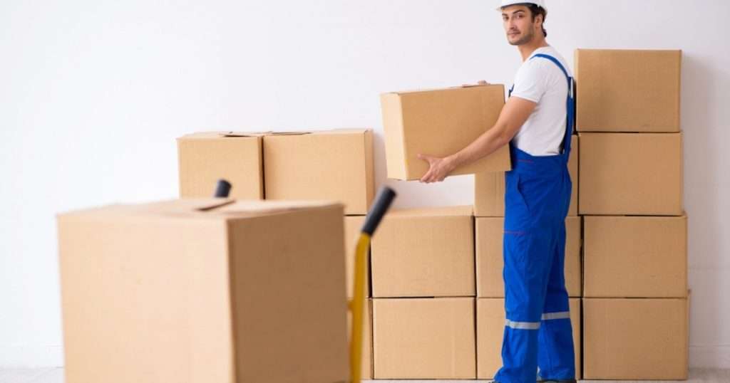 A professional and committed moving professional with a Tempe moving company holding a box past other boxes