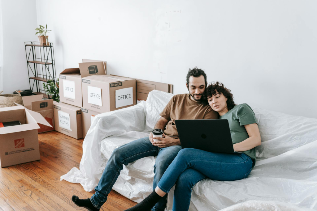 Couple with moving boxes looking at laptop