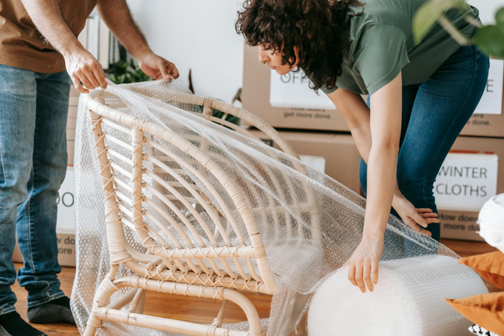 Woman carefully wrapping a wooden chair in bubble wrap to prepare it for a long distance move