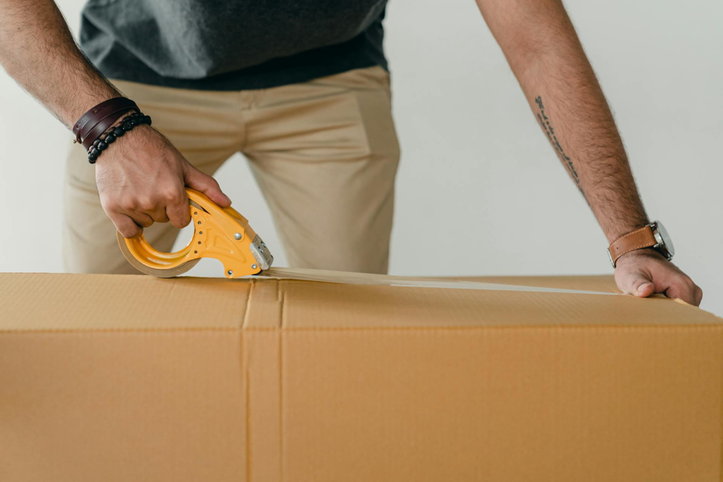 Close up of man closing a box with packing tape.