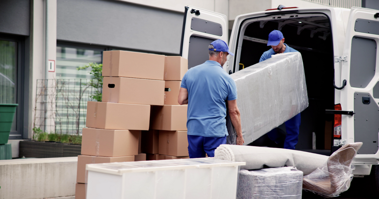 Two movers unloading furniture from the back of a moving van.